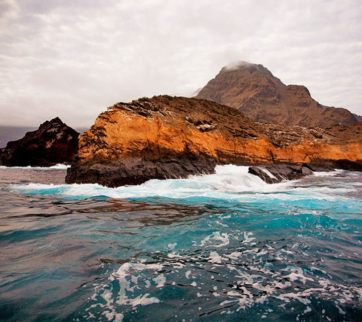 Waves crash on an island in the Galapagos during a rainy day